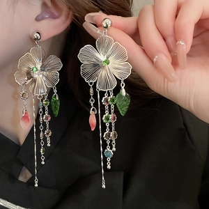 Close-up of floral tassel earrings with silver finish and colorful gemstones on model