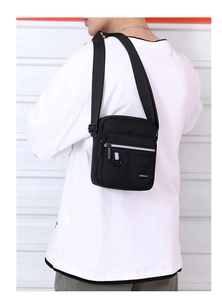 Detail view of the black nylon crossbody bag with reflective strip and functional D-ring