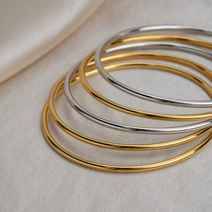 Minimalist 18K gold and silver stainless steel bangles set on premium silk fabric
