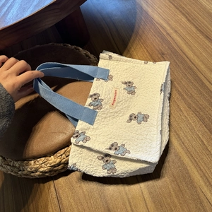Dettaglio della borsa trapuntata con motivi di orsetti e manici in tessuto blu