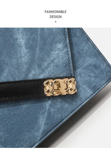 Detail of blue denim shoulder bag with black leather strap and gold woven metal lock