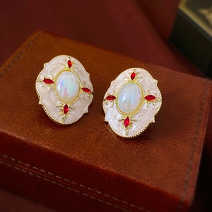 Gros plan de boucles d'oreilles dorées vintage avec opale et pierres rouges