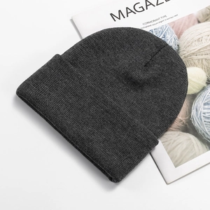 Detail of dark grey knit beanie showing high-quality ribbed texture on a white background