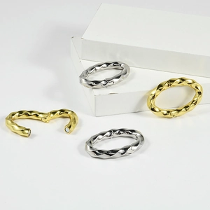 Detail view of twisted metal hoop earrings with magnetic clasp in gold and silver finish
