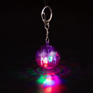 Detail of purple disco ball keychain with glowing LED effect on black background