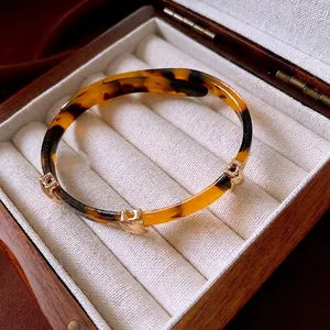 Vintage leopard print resin bangle with golden metal accents on a velvet jewelry box