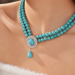 Detail view of a double-layered turquoise bead necklace with a crystal drop pendant