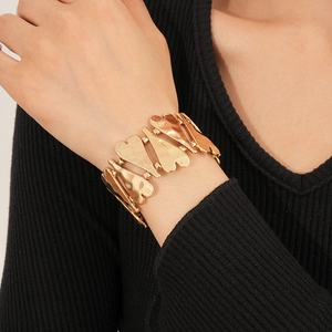 Détail du bracelet à maillons cœur doré avec texture métal martelé porté au poignet