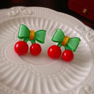 Gros plan de boucles d'oreilles cerise avec perles rouges brillantes et nœud en résine