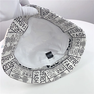 Inside view of white cotton newspaper print bucket hat showing washing label and lining