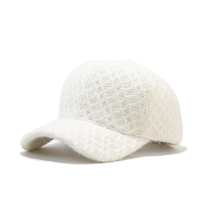 Detailed close-up of white knitted baseball cap with textured plush knit and hollow pattern