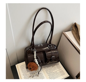Detail of dark brown patent leather shoulder bag with pockets and cute plush bear charm