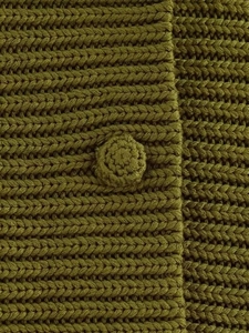 Detailed close-up of olive green chunky knit fabric with a matching crochet button