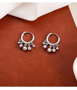 Detailed macro view of silver hoop earrings with hanging polished bead charms on leather