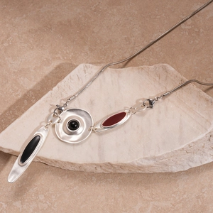Détail du pendentif géométrique avec émail noir et rouge sur une chaîne serpent argentée