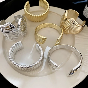 Collection of textured gold and silver metal open bangles in a ceramic tray