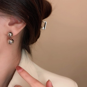 Close-up of elegant silver double-ball drop earrings with a polished mirror finish on model