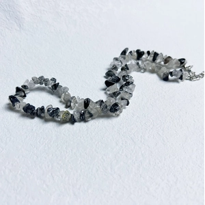 Macro shot of natural irregular black and clear stone chips with a silver lobster clasp