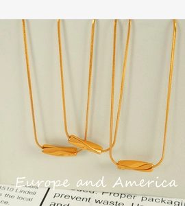 Detail of three golden geometric twist pendants on delicate chains with a modern luxury feel