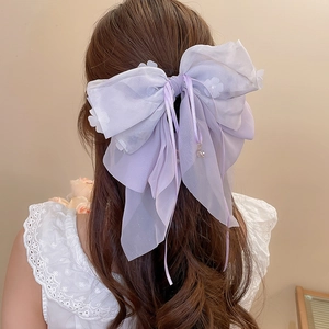 Dettaglio del fiocco in organza lavanda con ricami floreali sui capelli della modella
