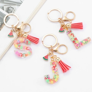 Detail of S, J, L resin alphabet keychains with fruit slices, watermelon charm and pink tassel