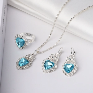 Detail of silver alloy jewelry set featuring blue heart crystals on white silk background
