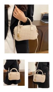 Detail of hand-woven beige Boston bag with golden knot charm in office setting