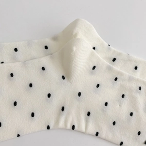 Vue détaillée de chaussettes en coton blanc à pois noirs avec des bords-côtes élastiques