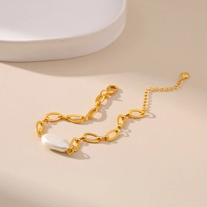 Elegant gold chain bracelet with baroque pearl and lobster clasp on neutral background