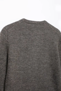 Detailaufnahme der feinen Strickstruktur und Schulternaht an einem braunen Pullover