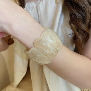 Detail of wide acrylic link bracelet with marble texture worn on a woman's wrist