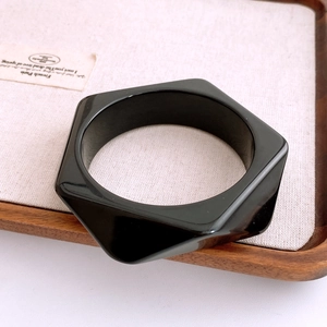 Gros plan d'un bracelet géométrique noir épais en acrylique avec une finition miroir poli