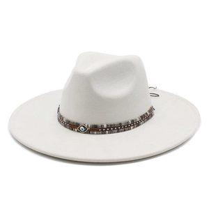 Close-up of white fedora hat featuring woven band and blue evil eye pendant detail