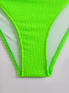Detailed macro view of fluorescent green crinkle fabric on bikini bottoms with soft lining