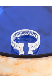 Macro shot of silver bow ring with hollow lattice design on blue crystal surface