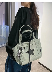 Detail of light green waterproof tote bag featuring star print and checkered plush ball