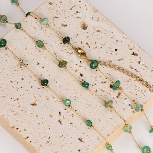 Golden necklace with emerald green crushed stones on a natural stone background
