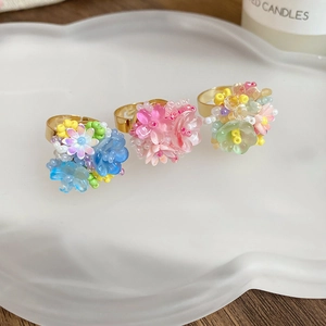Dettaglio di tre anelli a fiore fatti a mano con perline di resina in colori assortiti