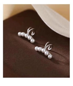 Detail shot of silver plated pearl ear cuffs with five white pearls on brown velvet