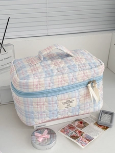 Detailed view of quilted heart pattern and blue ribbon zipper on colorful checkered makeup bag