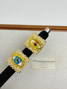 Detail of bohemian gold square rings with evil eye resin and pearl embellishments
