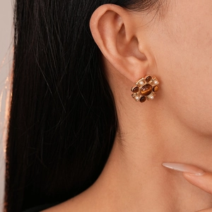 Detail of vintage flower earring with amber gemstone and pearls worn by a model