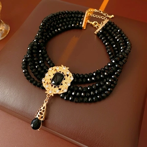 Detail showing vintage multi-layer black bead necklace with gold engraved centerpiece and stone