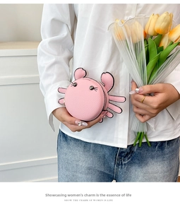 Pink crab-shaped leather coin purse with metallic eyes held by a model with tulips