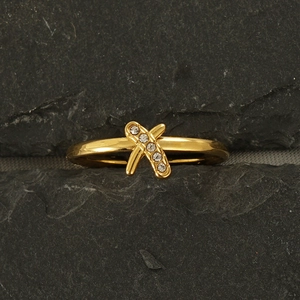 Macro shot of 18k gold plated stainless steel X-shaped ring with inset crystals on rock