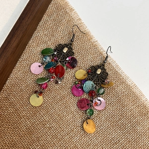 Close-up of Bohemian layered shell fringe earrings with vintage bronze floral metalwork