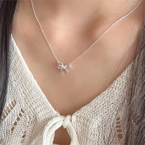 Elegant 925 sterling silver bow pendant necklace worn by a model on a lace collar