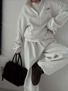 Detail of grey sweatshirt set featuring red The Bearrrr embroidery on chest and leg