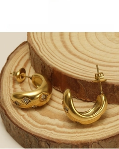 Détail macro de boucles d'oreilles C épaisses plaquées or 18K avec zircons en forme d'étoile