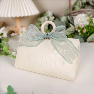 Detailed view of beige paper gift box with a wooden ring handle and green ribbon bow